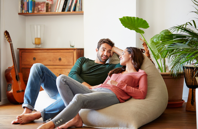 Shot of a smiling young couple talking together while relaxing on a beanbag sofa at home