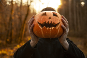 A young man holds a pumpkin lantern