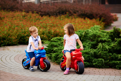 Niños jugando en el parque con sus motos de juguete