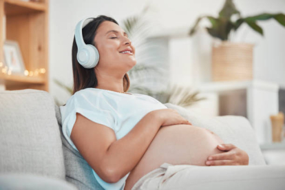 Mujer embarazada con auriculares escuchando música