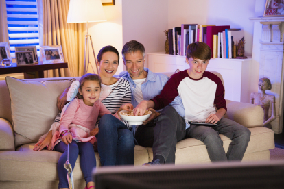 Familia comiendo palomitas y viendo la televisión