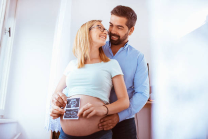 Mujer embarazada con su pareja sosteniendo una ecografía