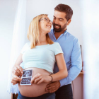 Mujer embarazada con su pareja sosteniendo una ecografía
