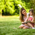 Una madre y su hija leyendo en el parque.