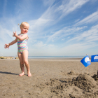Una niña jugando en una playa con Bandera Azul
